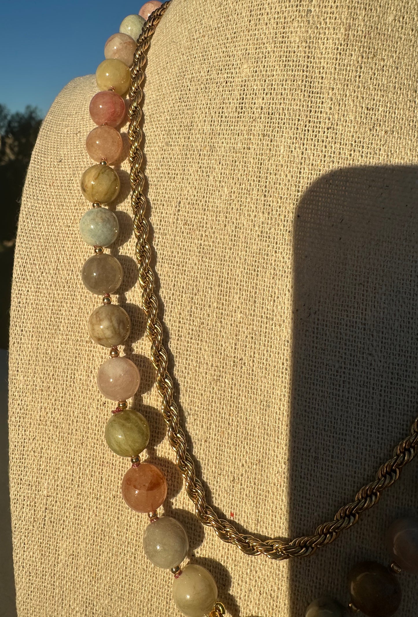 Close-up of multicolor beryl and morganite beads showing variation in color and gold-plated clasp detail.