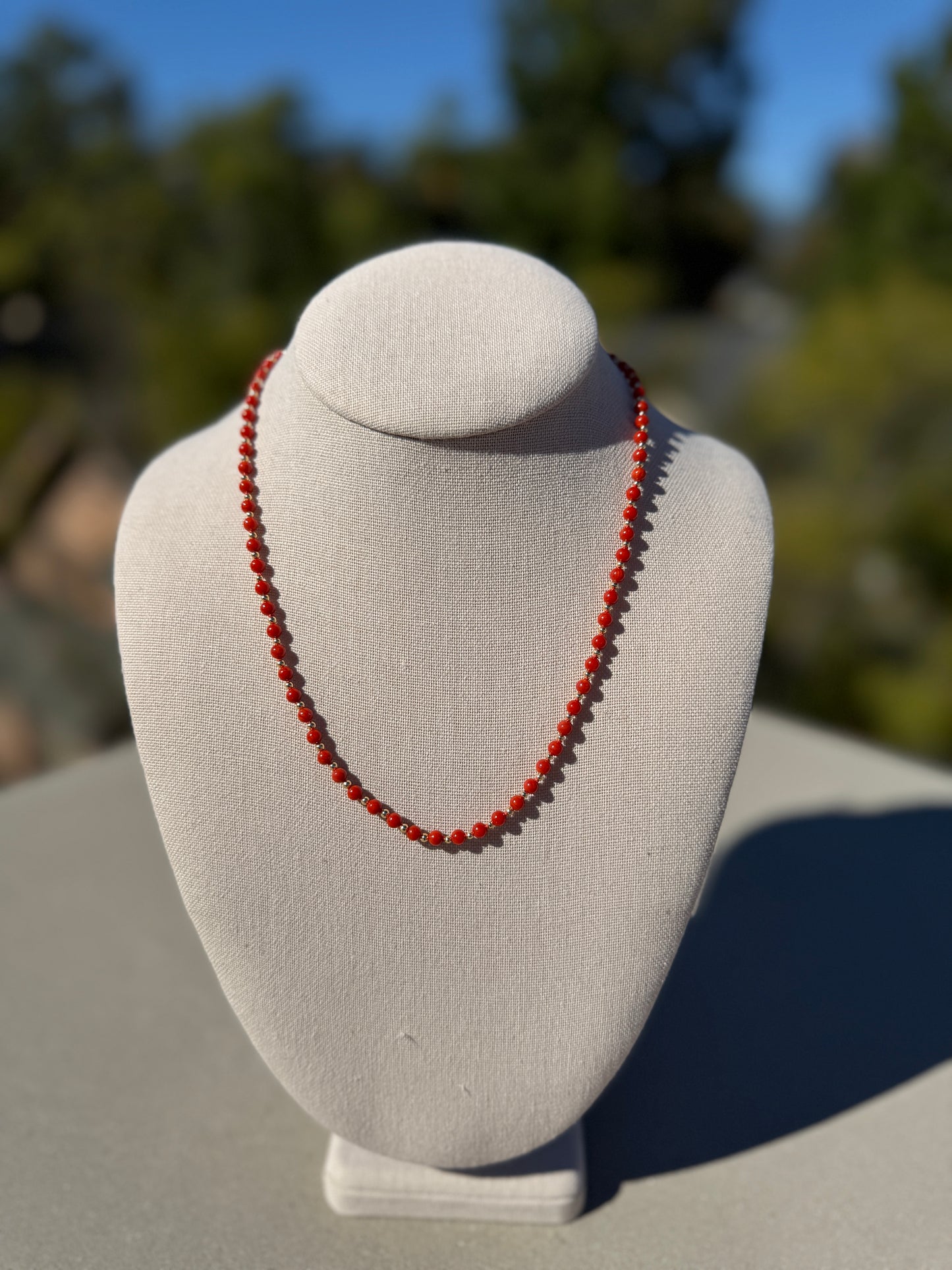 Coral beaded necklace, hand-knotted with gold-plated clasp, 19 inches long.