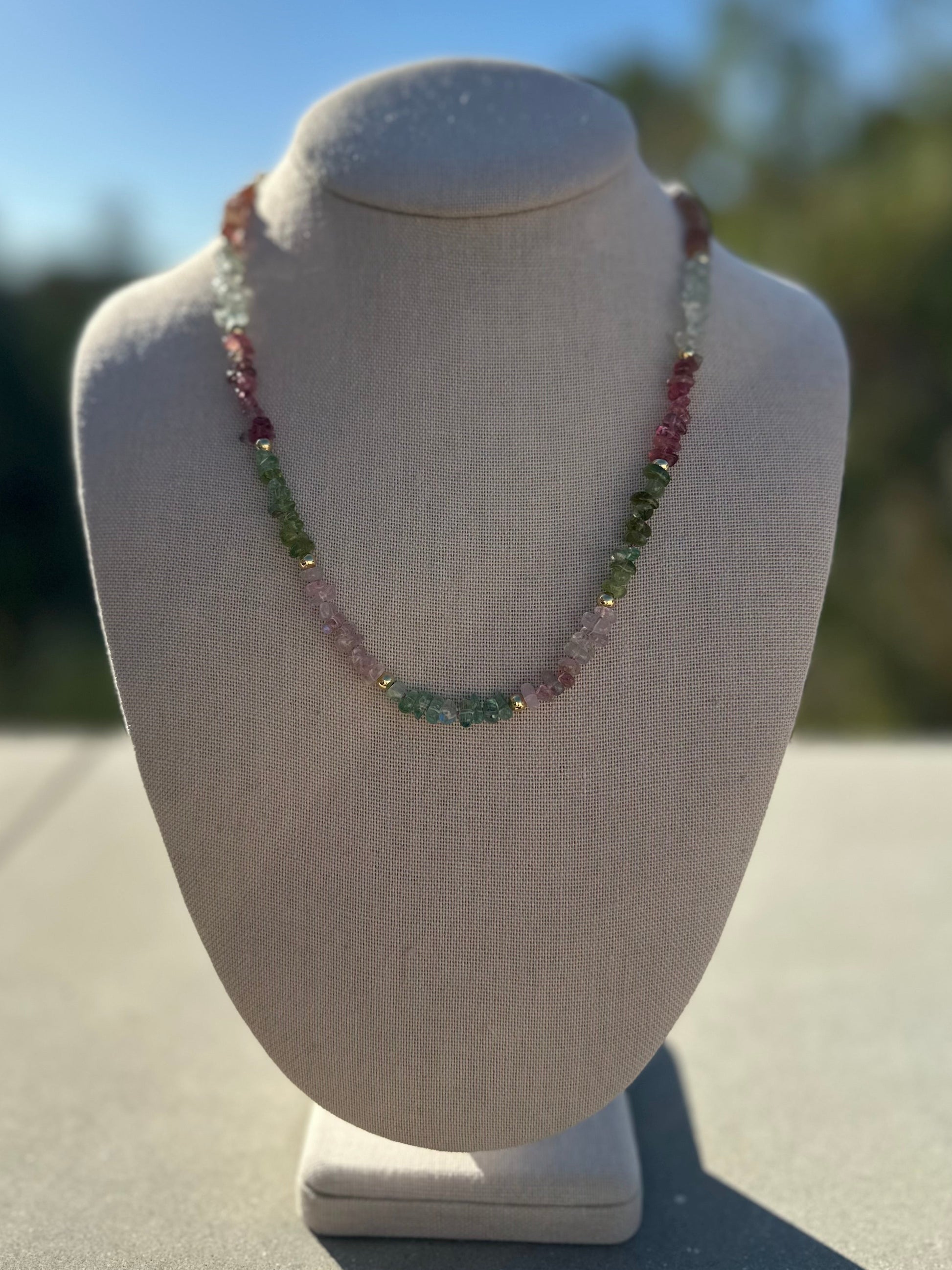 Necklace on a mannequin bust with a blurred outdoor background