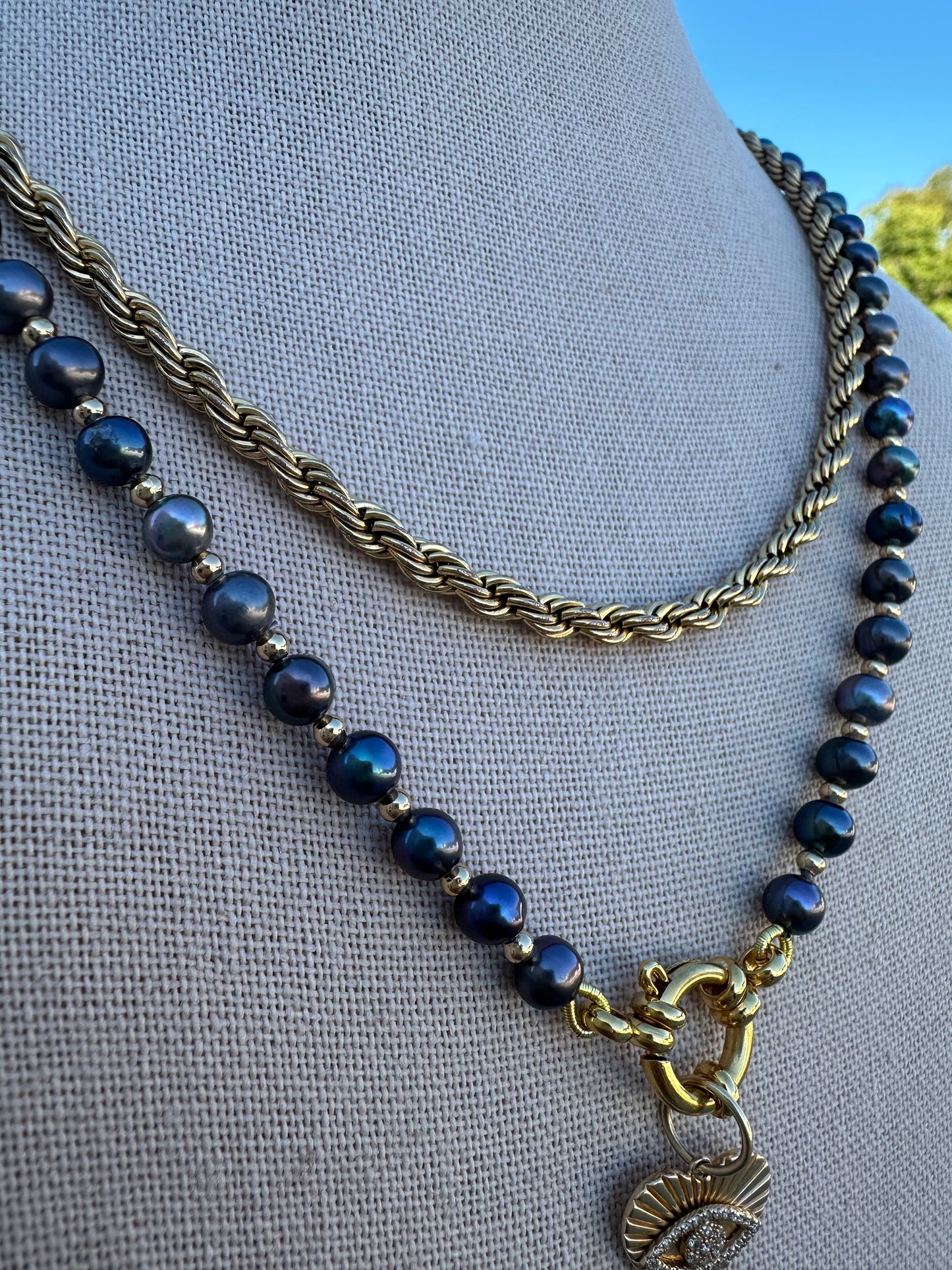 Close-up of black freshwater pearls with visible knots and gold-plated accent beads.