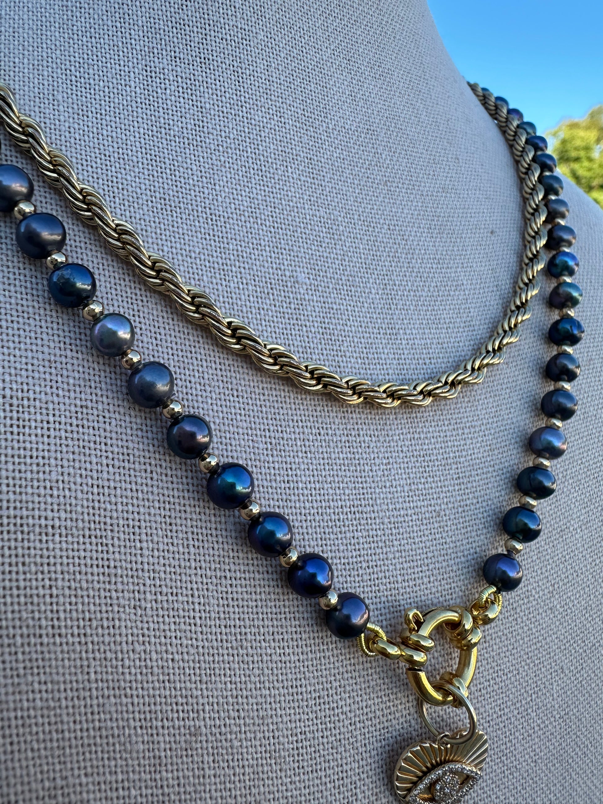 Close-up of black freshwater pearls with visible knots and gold-plated accent beads.