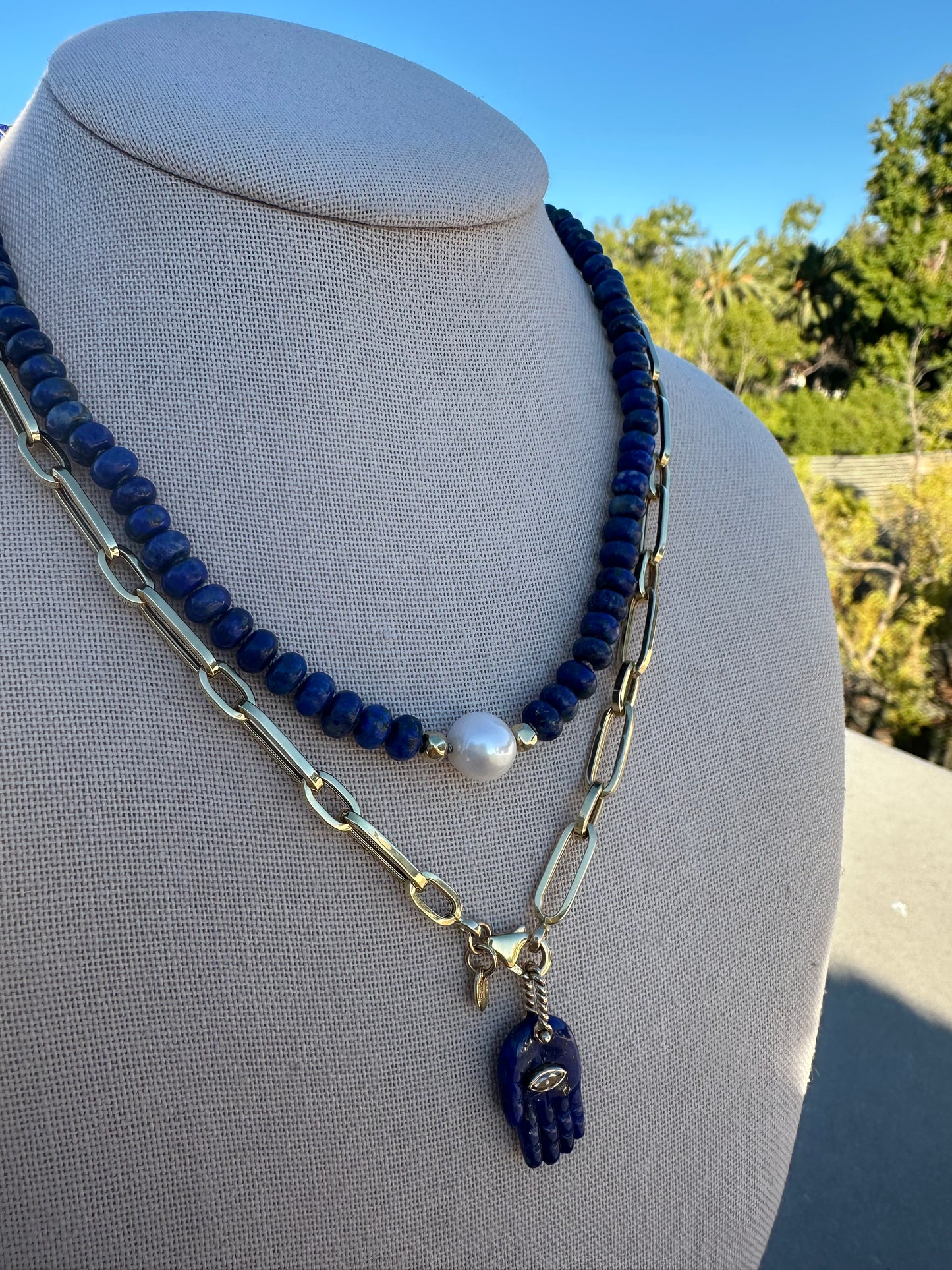 Close-up of lapis lazuli and freshwater pearl beads showing knot spacing and gold-plated accent.