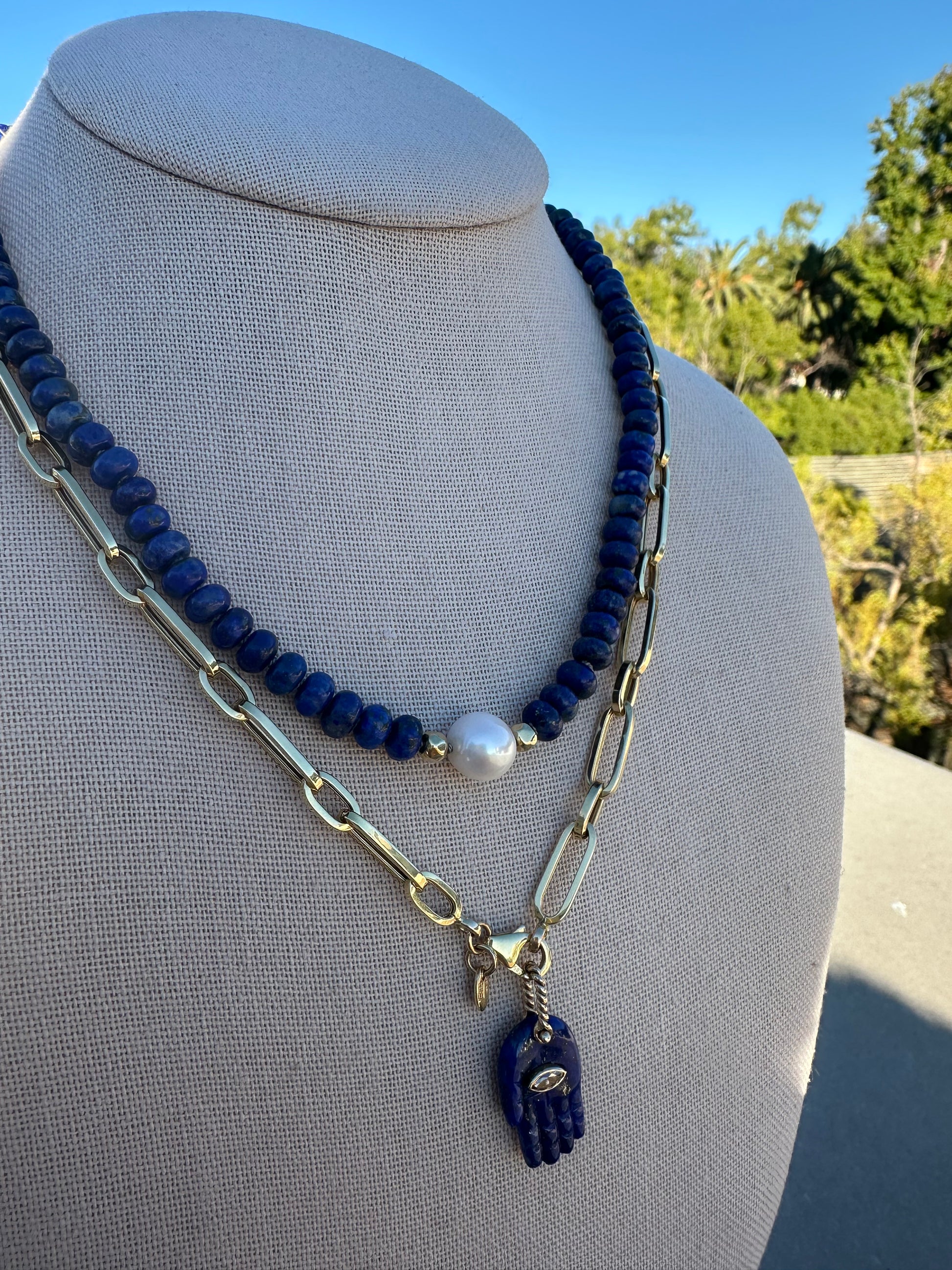 Close-up of lapis lazuli and freshwater pearl beads showing knot spacing and gold-plated accent.