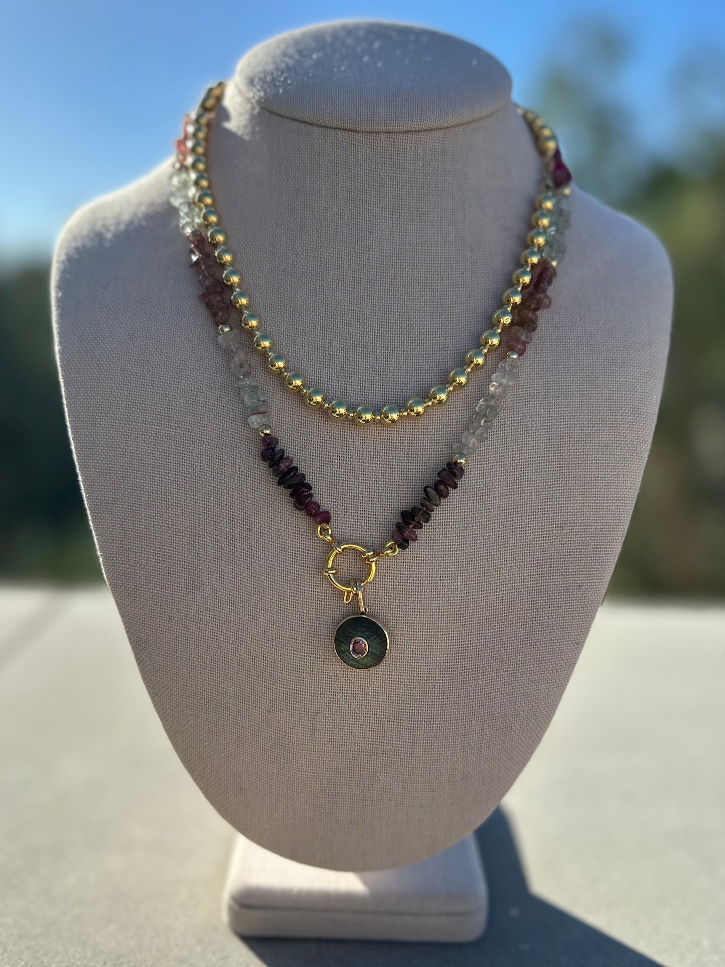Multi-color tourmaline necklace layered with gold chain and charm for styling example, items not included.