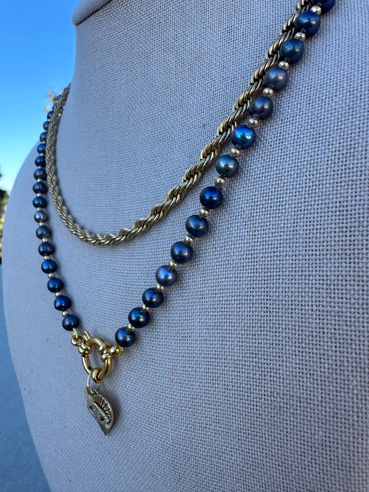 Detail of gold-plated clasp and adjacent pearls on silk thread.