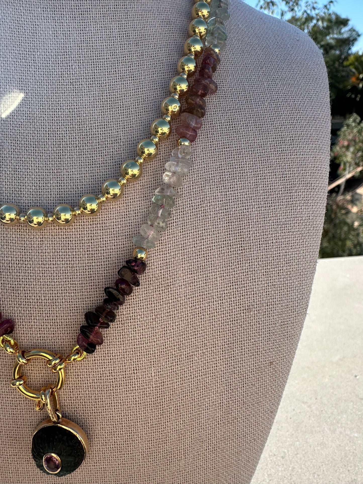 Close-up of multi-color tourmaline beads showing 2–6 mm size variation and gold-plated accents.