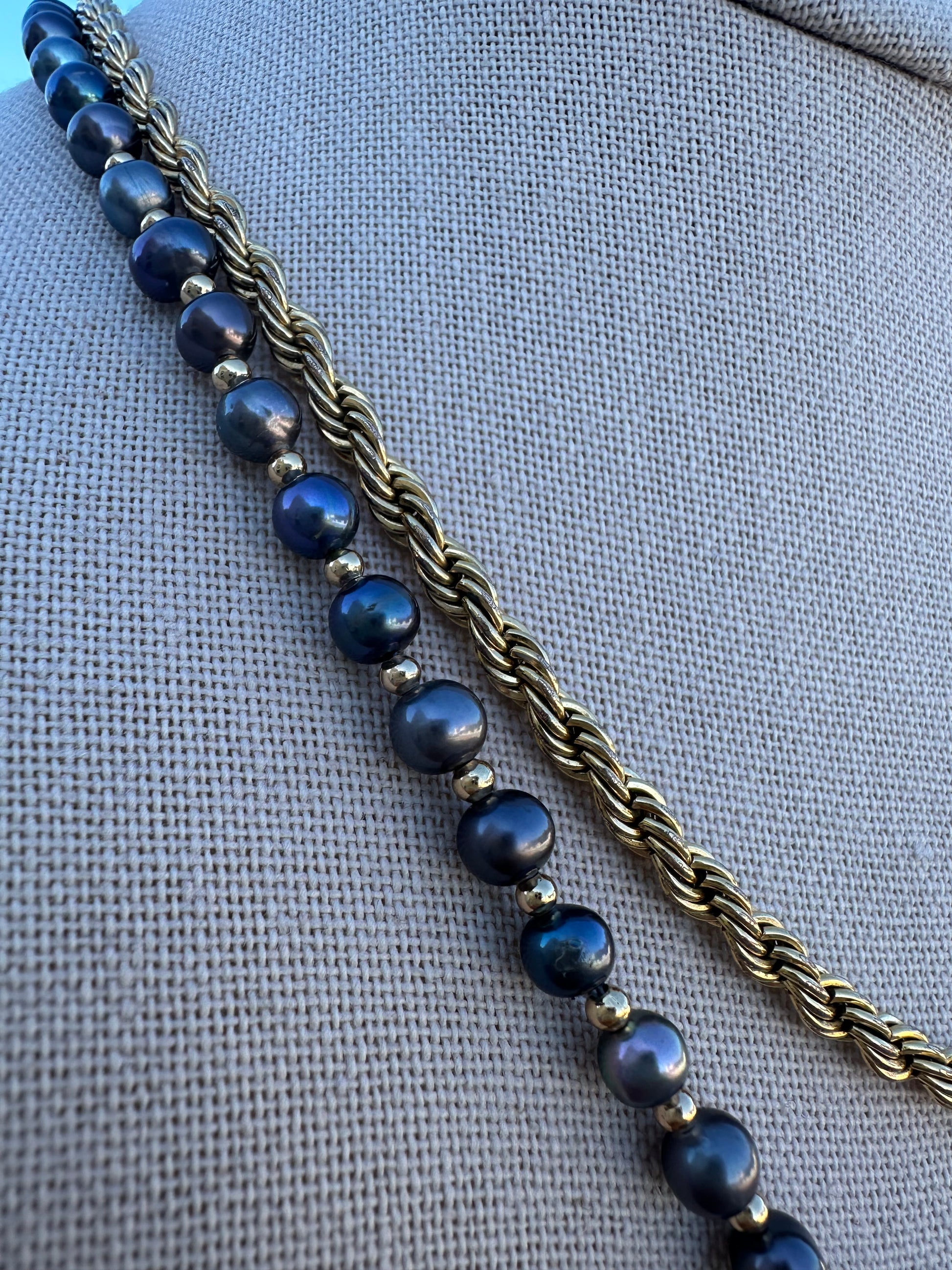 Close-up of pearl surface texture and knot spacing on black freshwater pearl necklace.