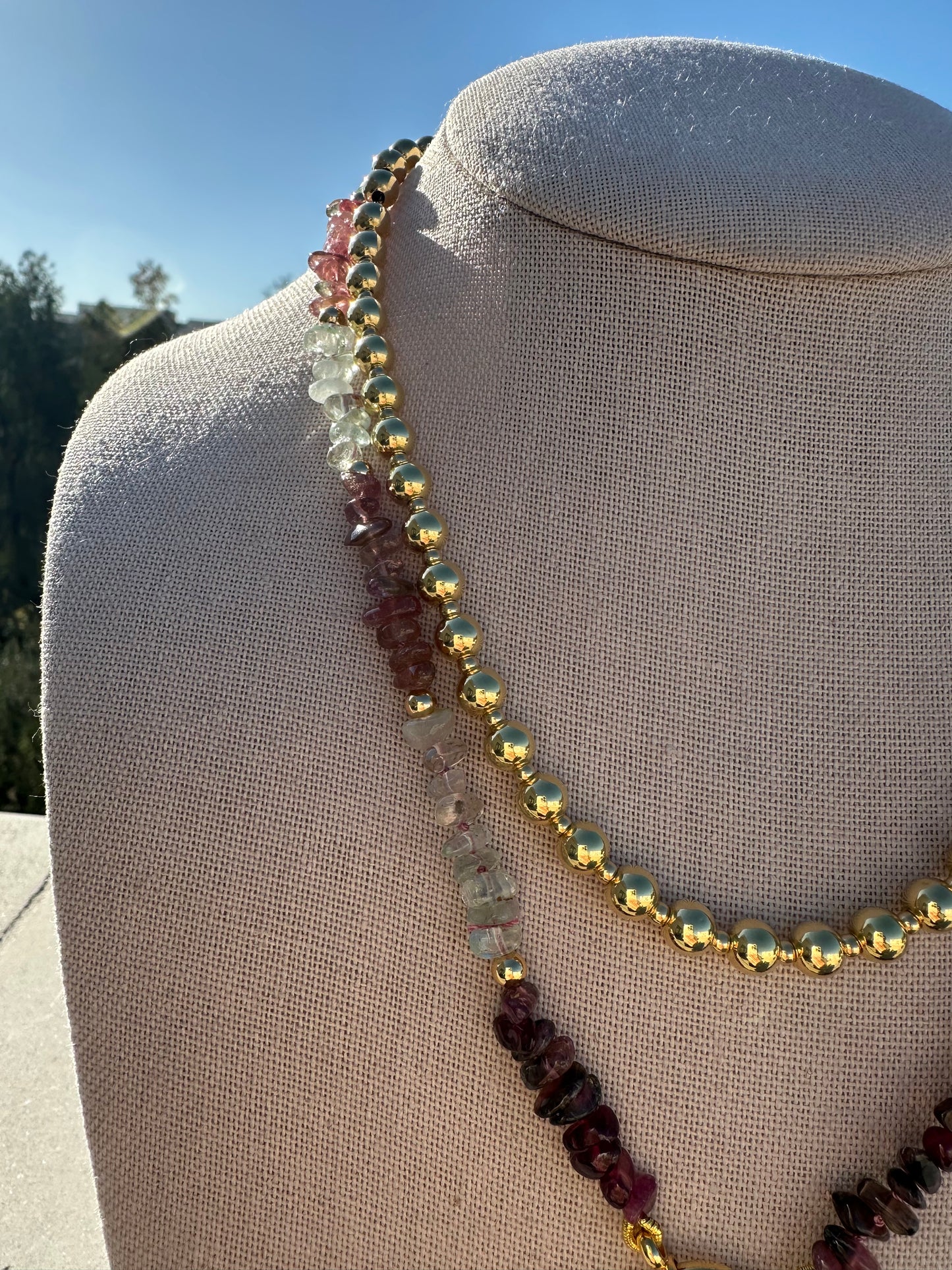 Close-up of multi-color tourmaline beads showing 2–6 mm size variation and gold-plated accents.