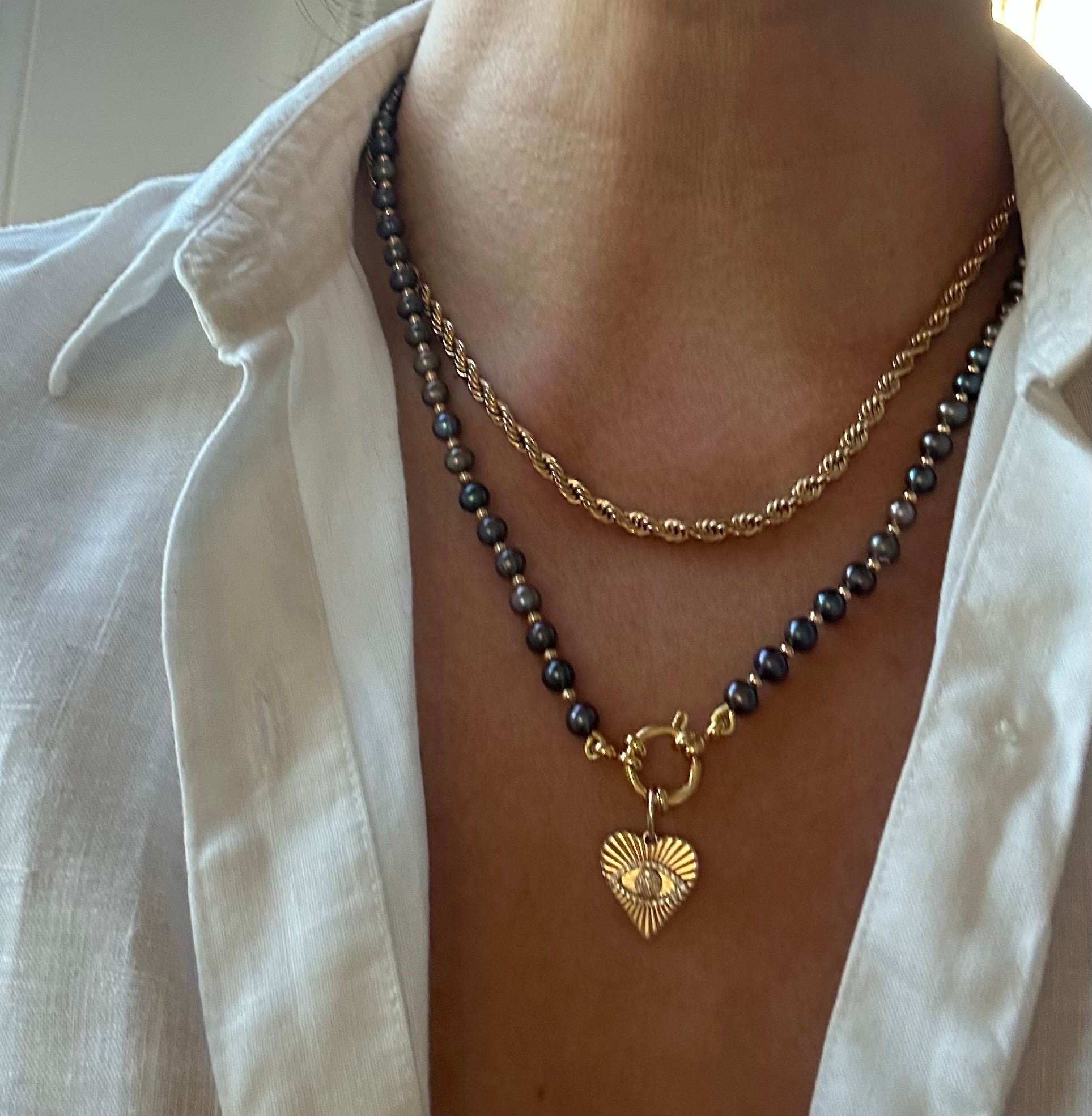 Person wearing black freshwater pearl necklace around neck, 21.5-inch strand length.