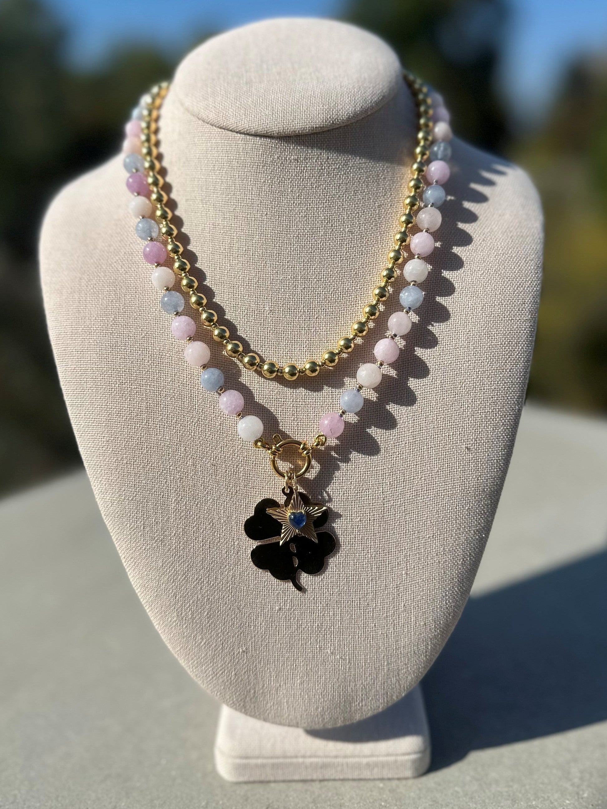 Morganite beaded necklace with gold-plated clasp on linen display under natural sunlight