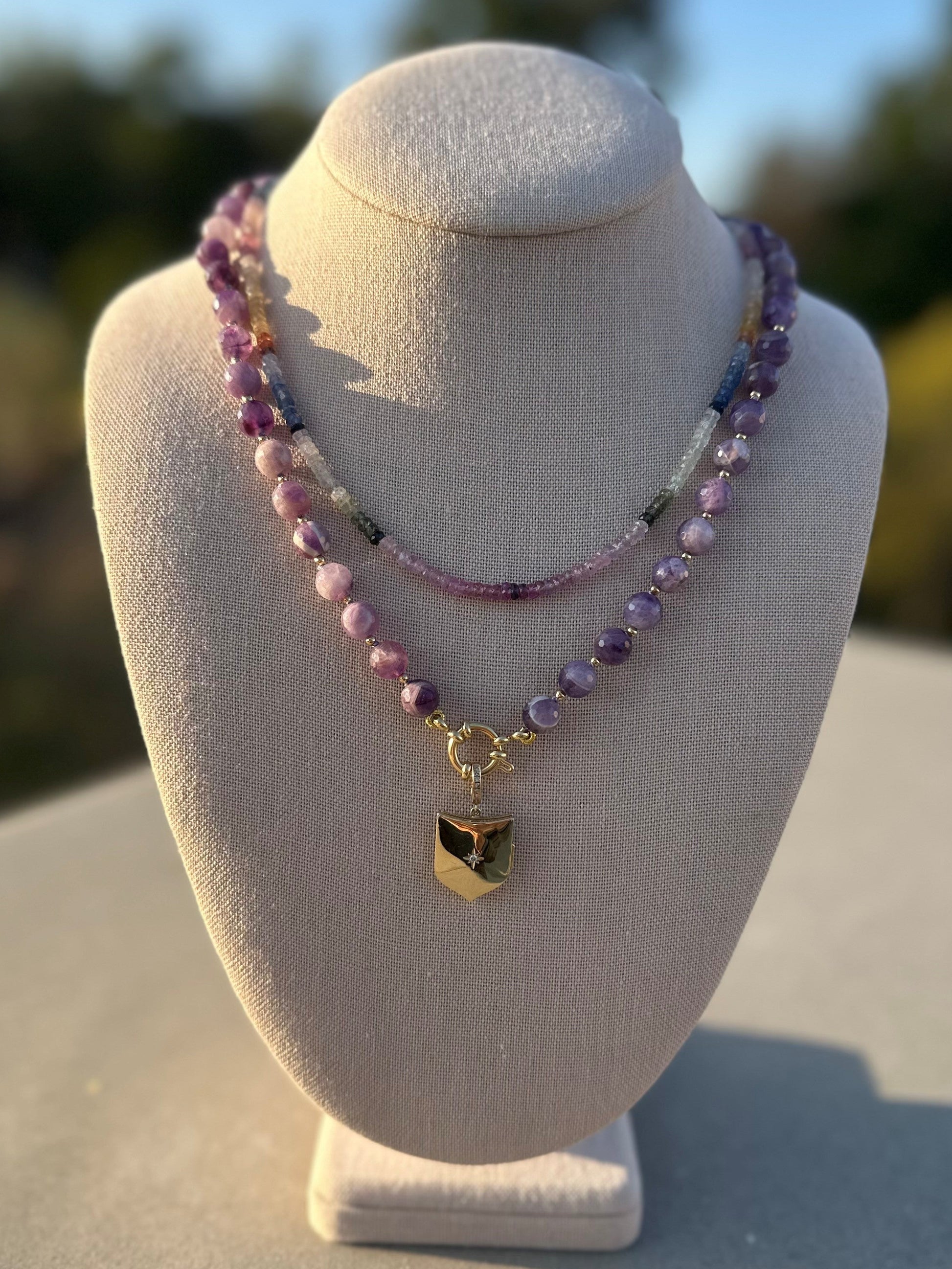 Amethyst beaded necklace with gold-plated clasp on linen display under natural light