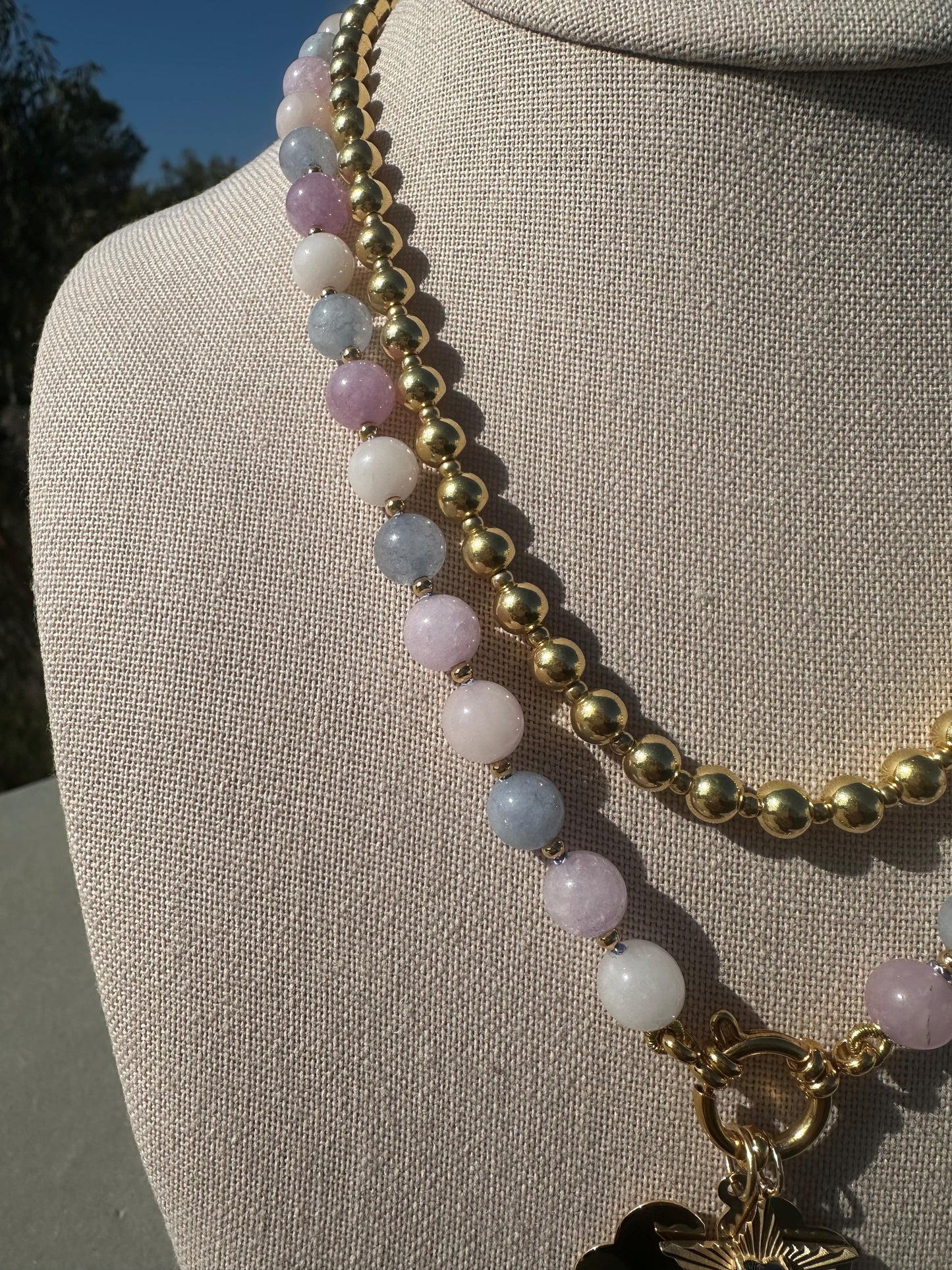 Close-up of pink morganite beads with gold spacer beads between knots