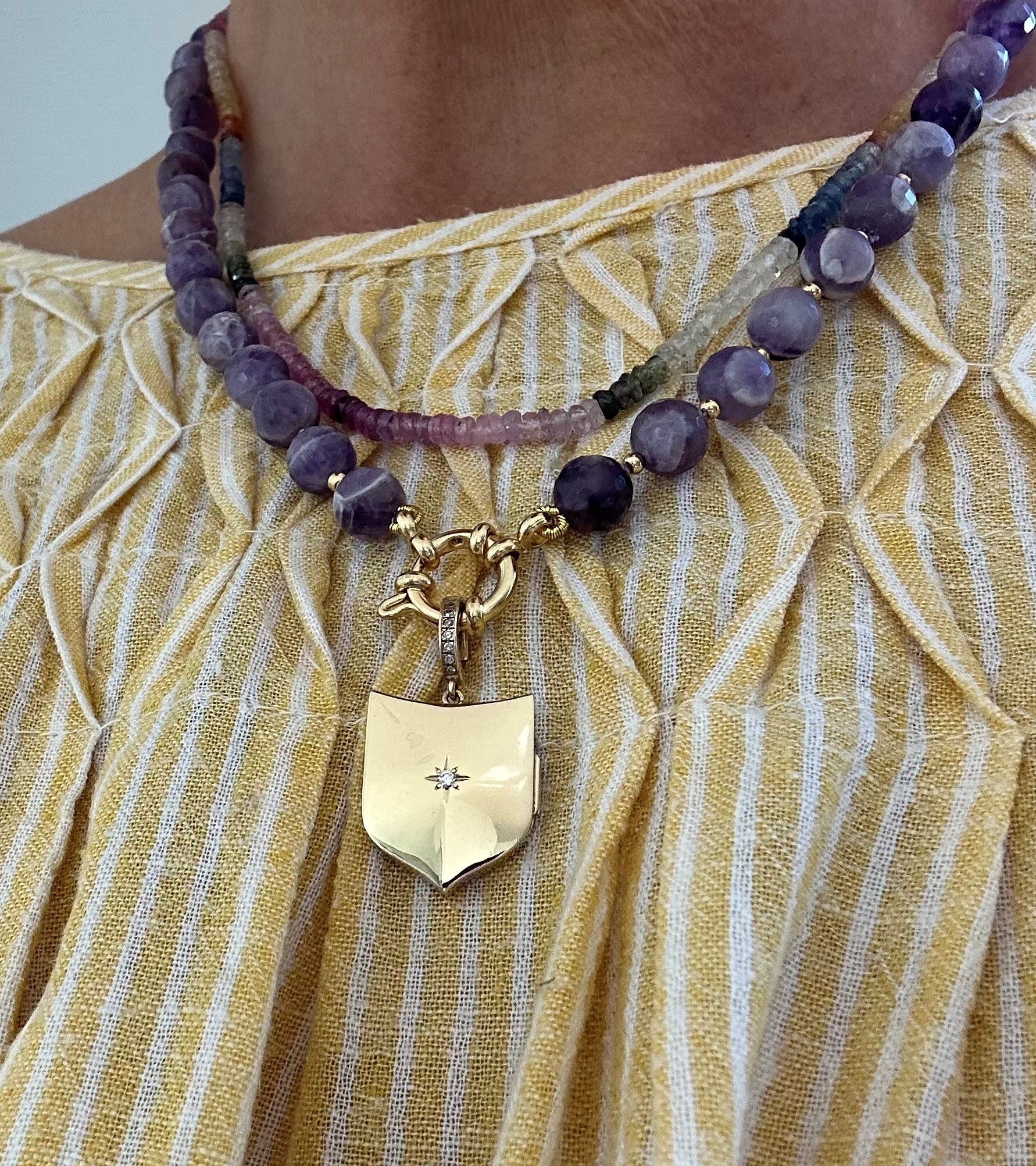 Amethyst necklace styled with additional chain and gold charm on model wearing yellow blouse