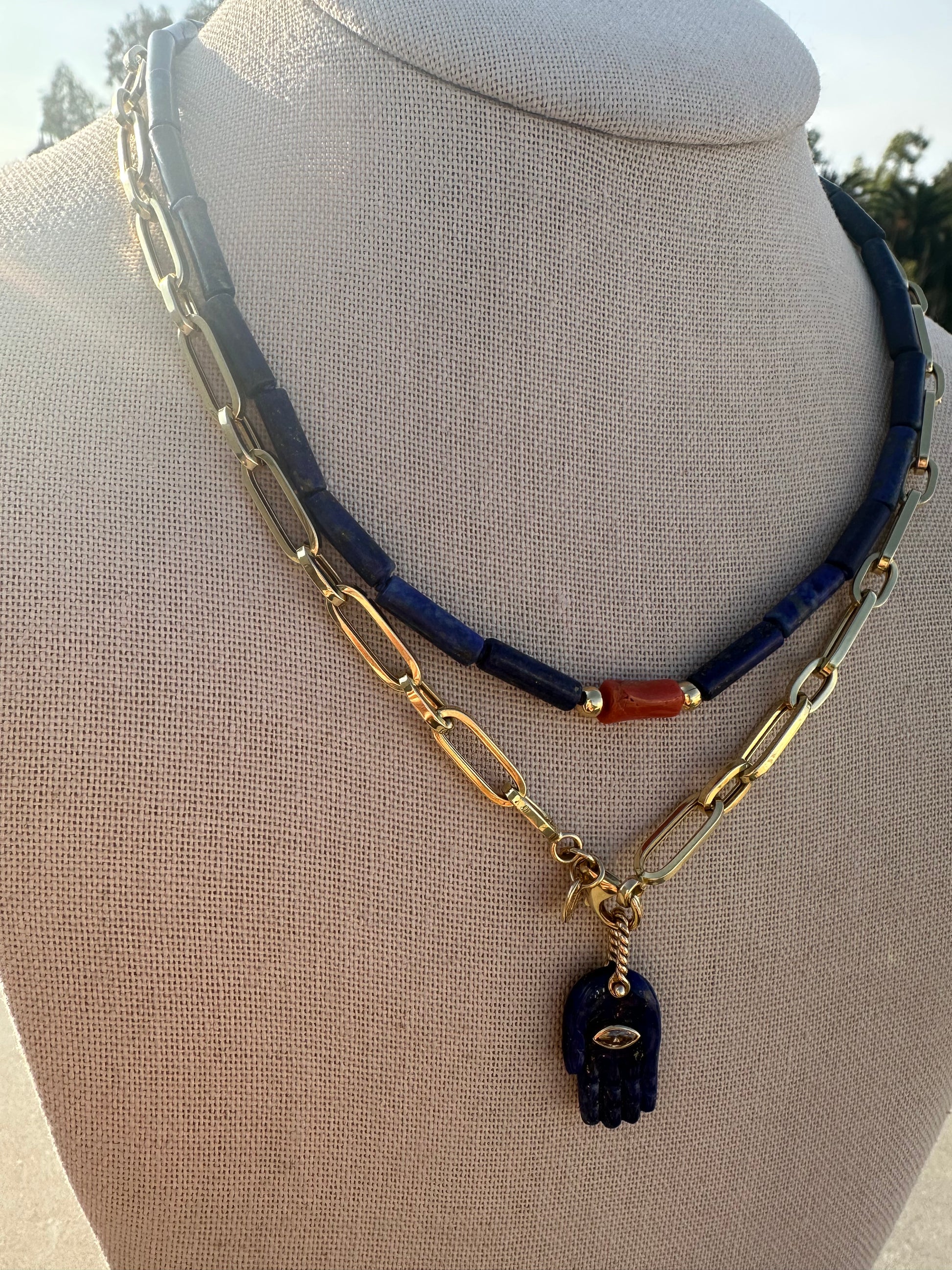Minimal lapis and coral necklace under natural sunlight on display bust