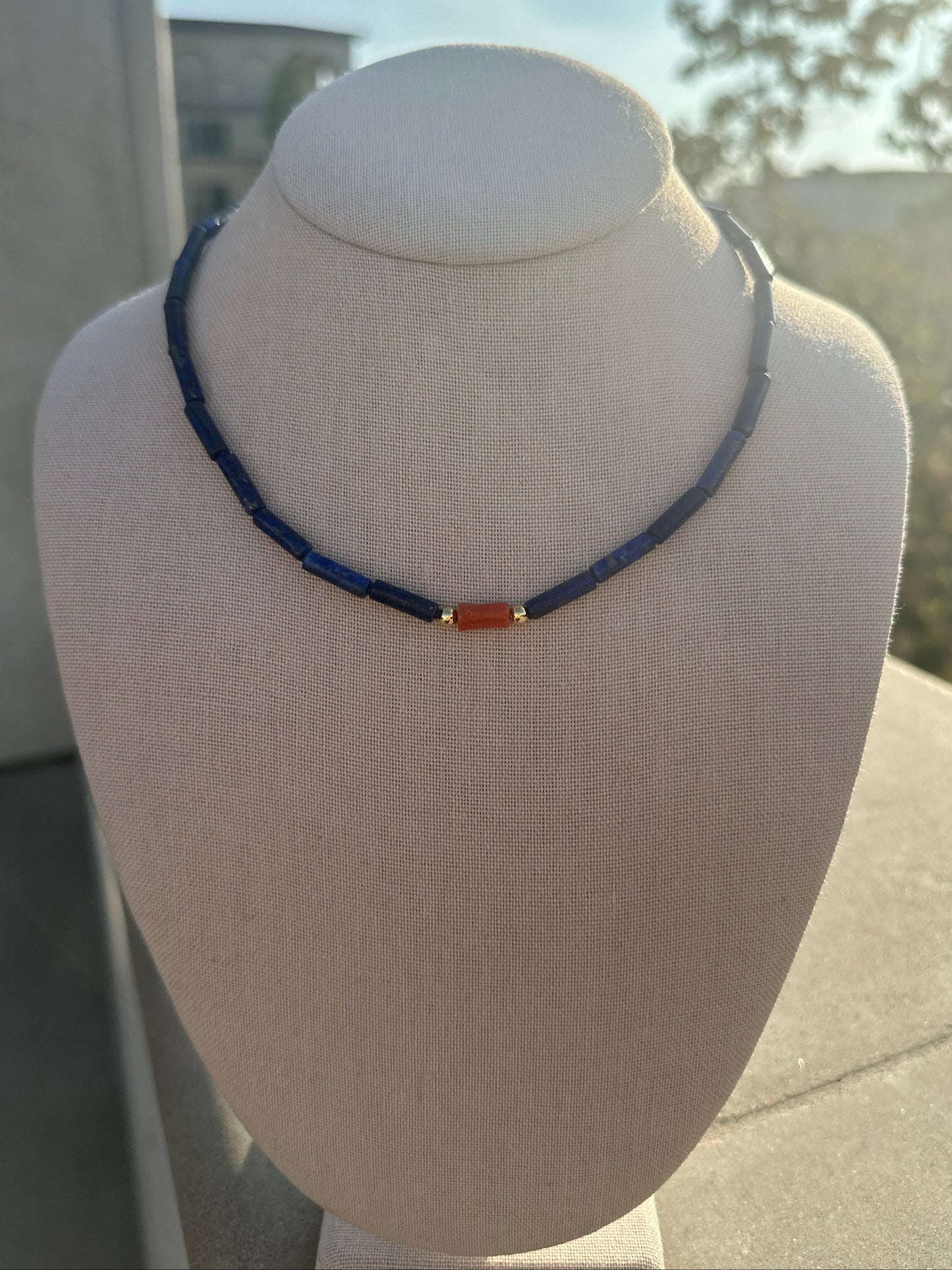 Lapis tube and coral bead necklace with gold-plated toggle clasp on linen display