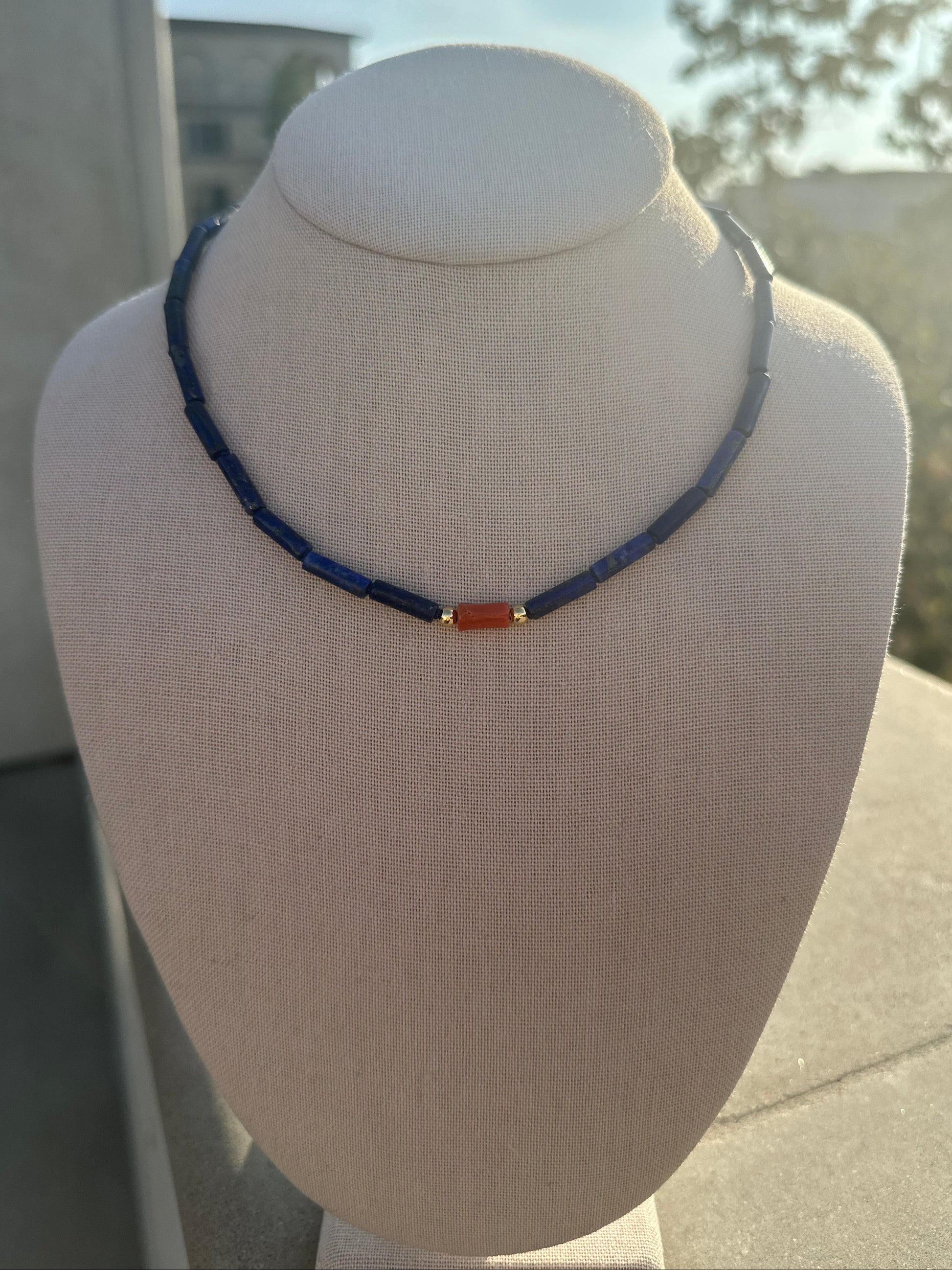 Lapis tube and coral bead necklace with gold-plated toggle clasp on linen display
