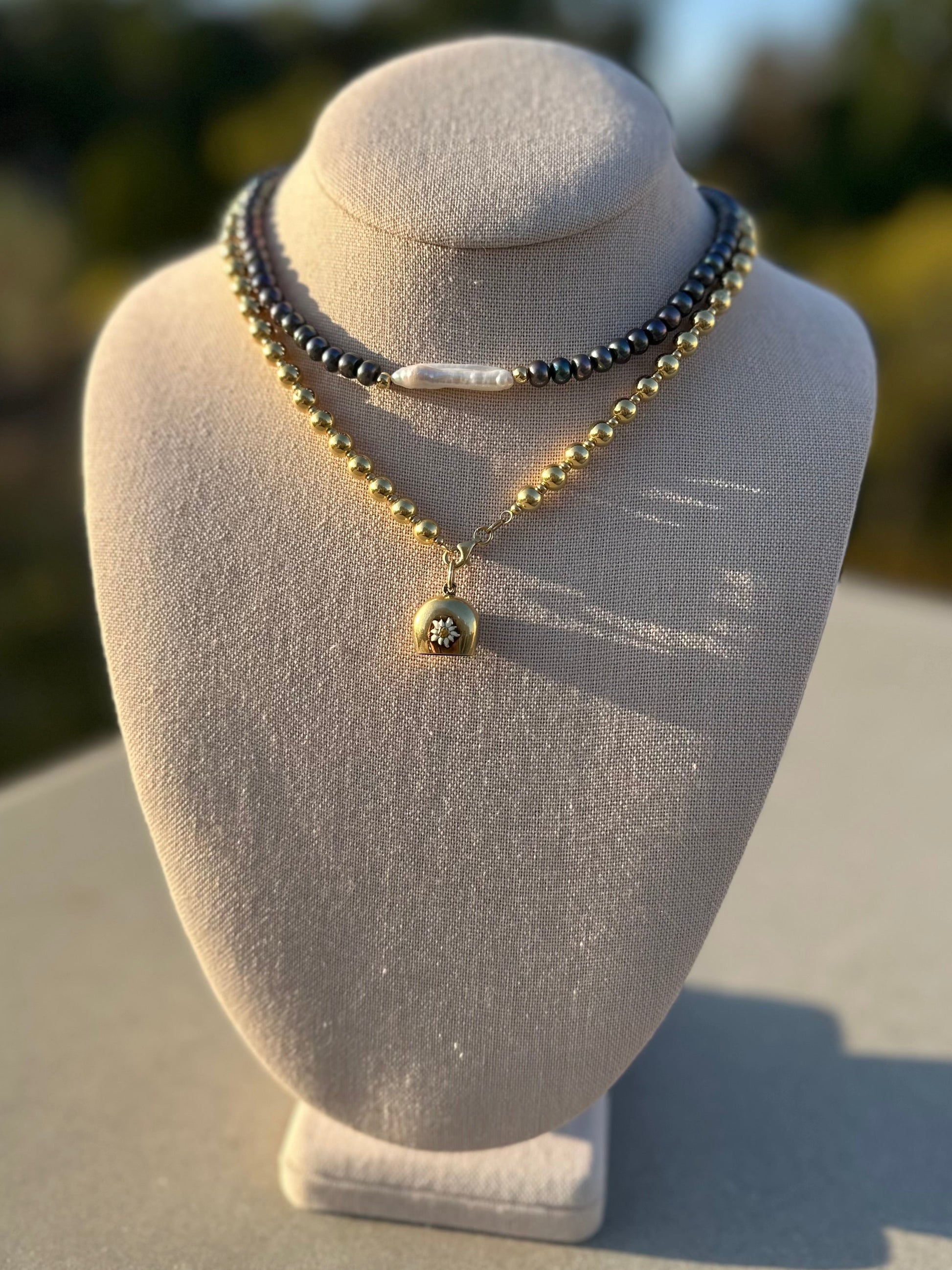 Black button pearl necklace with white stick pearl accent on linen display