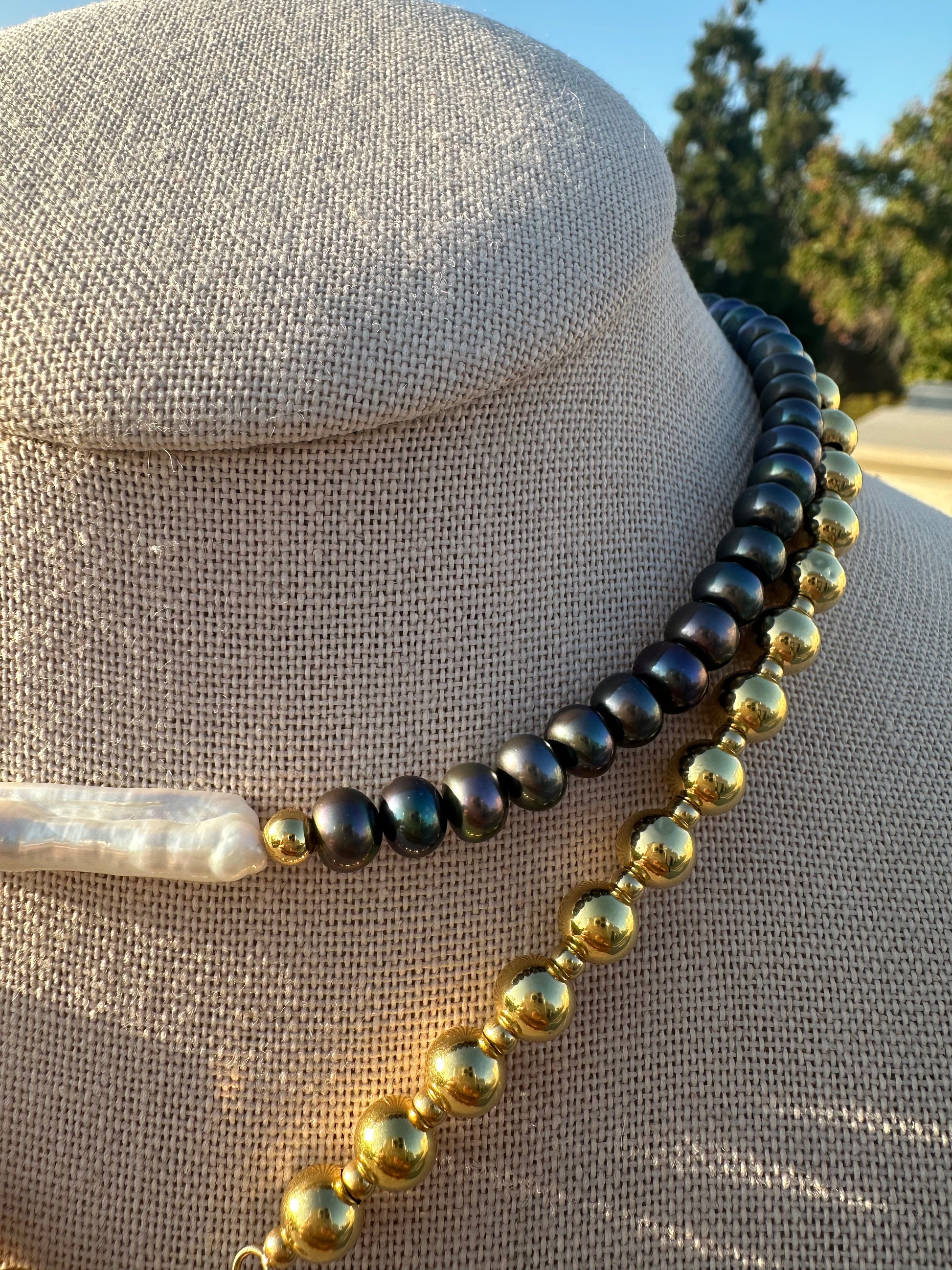 Close-up of black button pearls and gold-plated accent beads surrounding a white stick pearl
